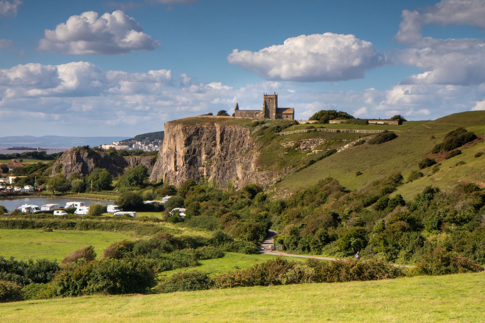 View across green fields to cliffs with a church on top